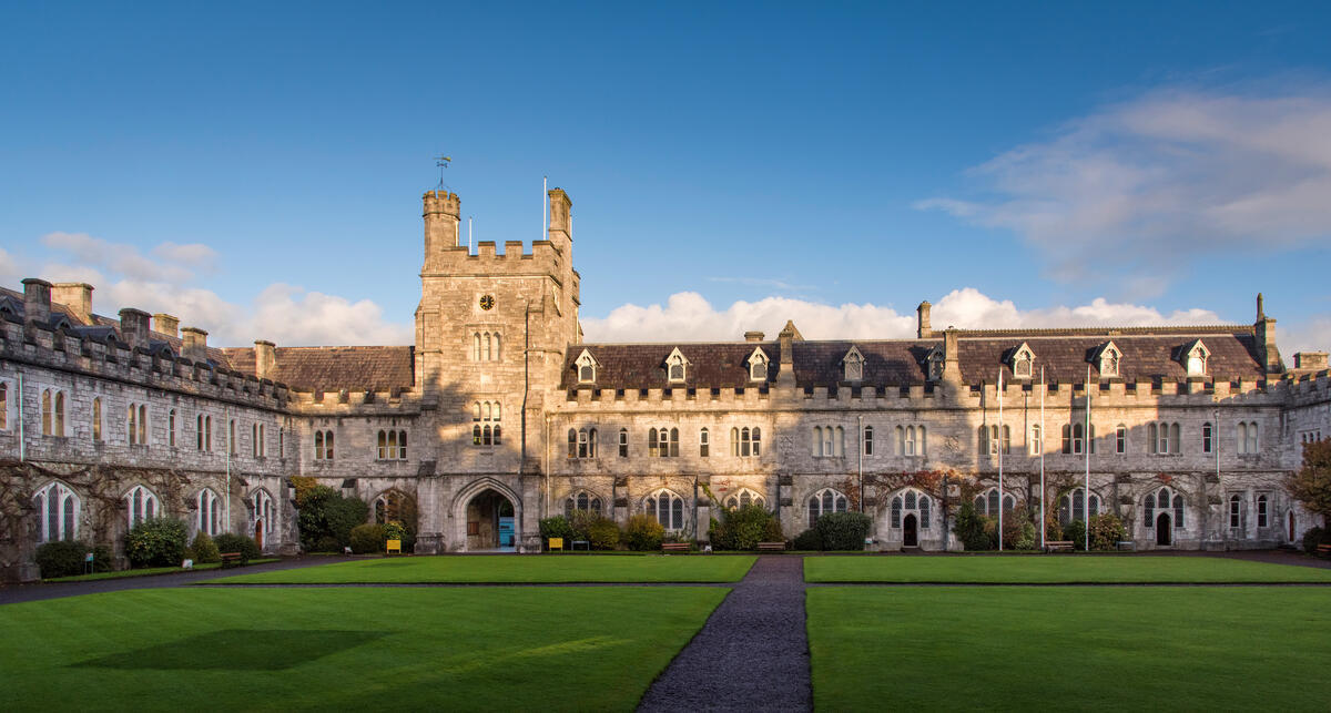 The historic stone quadrangle of University College Cork, with green lawns and warm evening light.